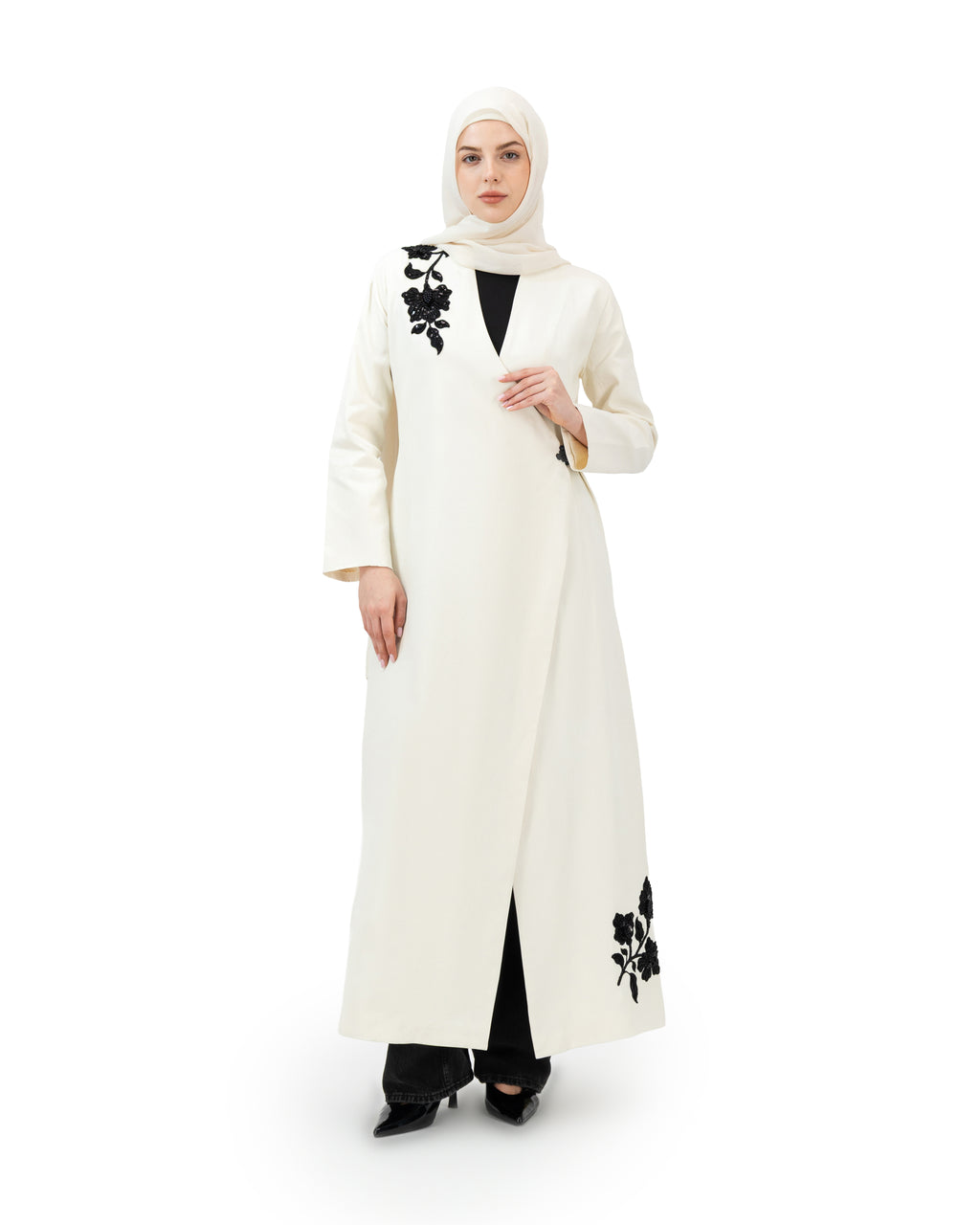 Woman wearing a white abaya with black floral patterns on a white background asain style