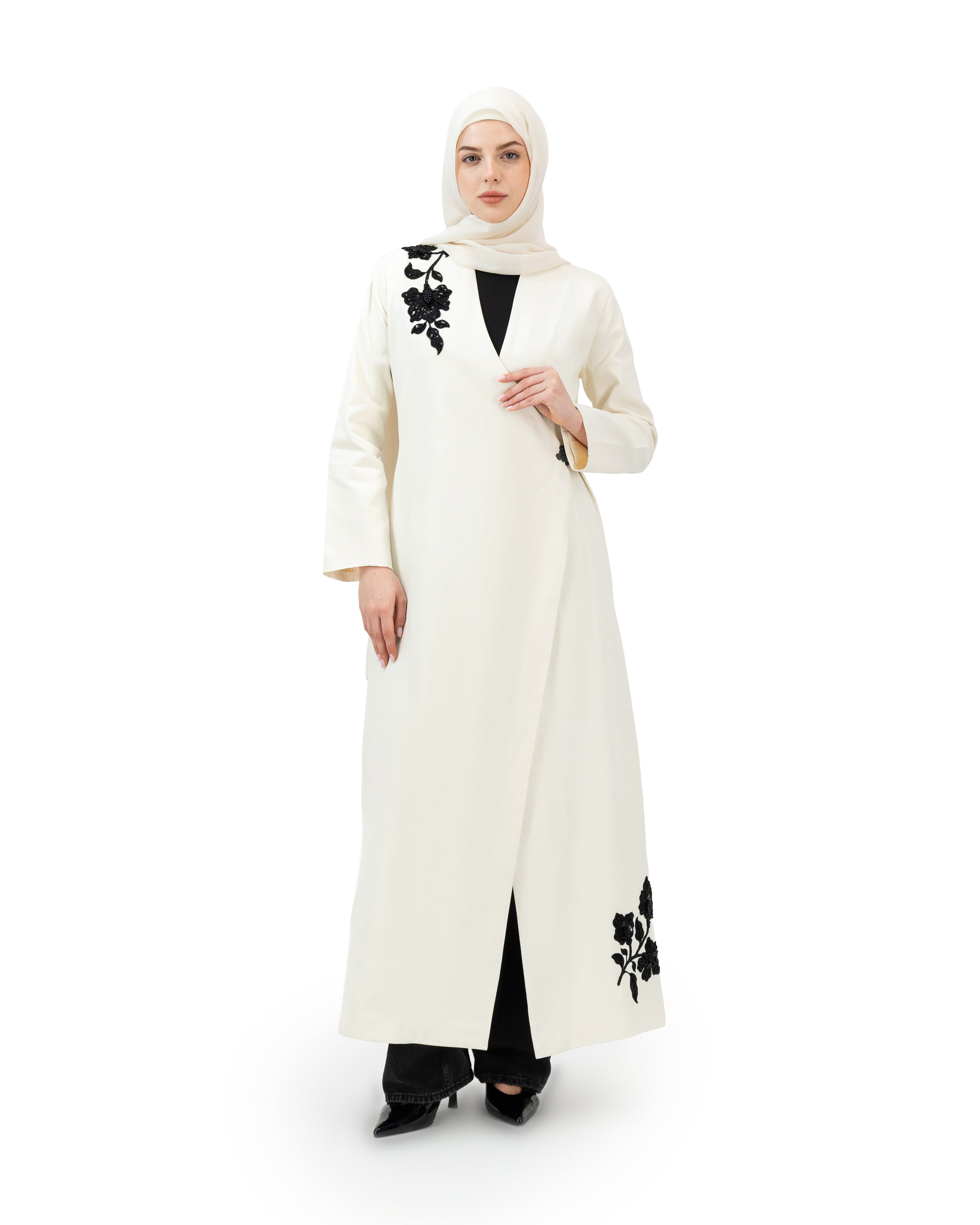 Woman wearing a white abaya with black floral patterns on a white background asain style
